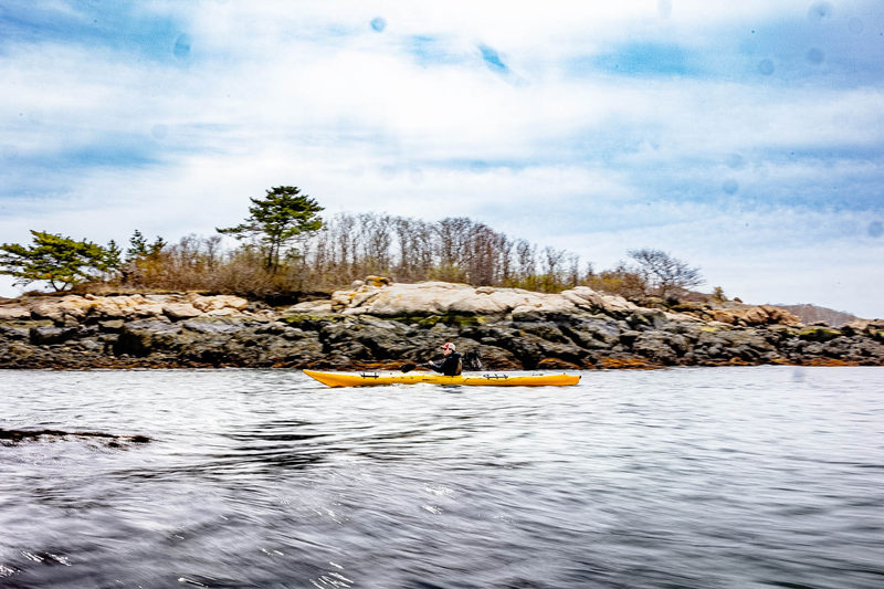 Sea kayaker passing a rocky island
