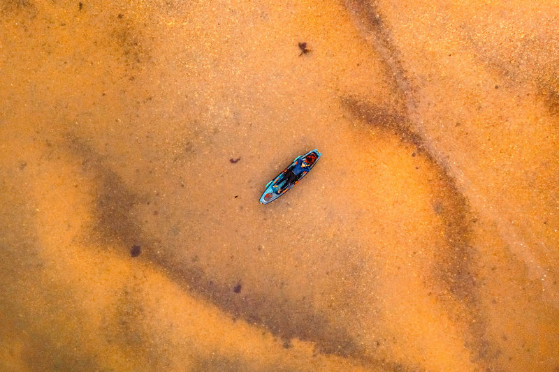Kayak crossing rust-colored water, aerial view