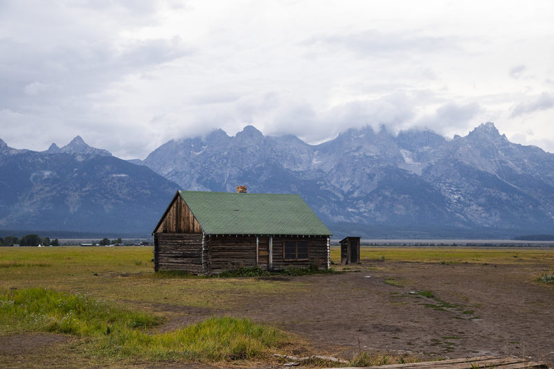 Historic log barn with green roof beneath the Grand Teton mountain range