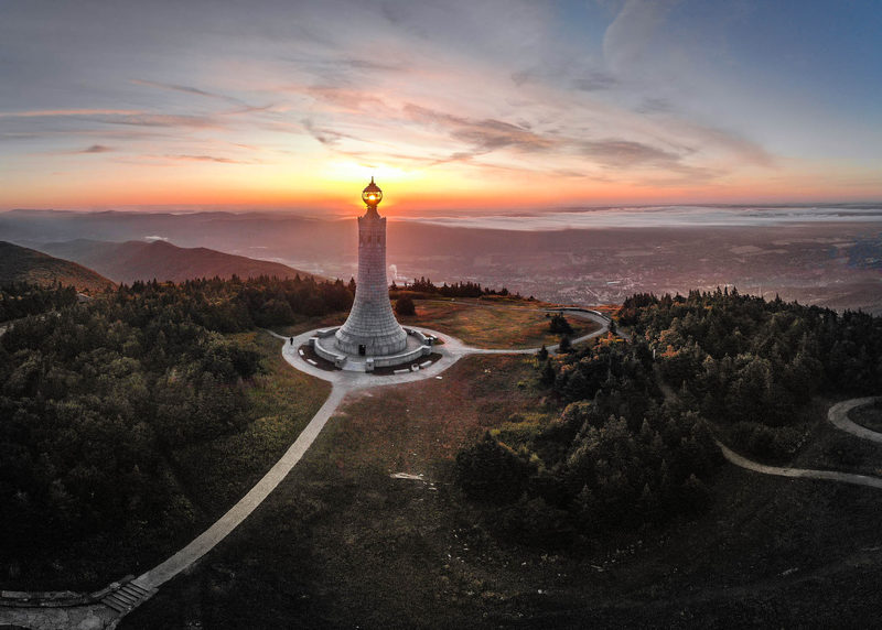 War Memorial Tower on Mount Greylock silhouetted against a colorful sunset above valley fog