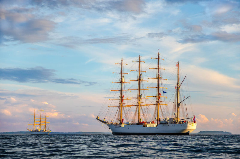 Two tall ships at sea off Nahant, MA under a pastel sunset sky