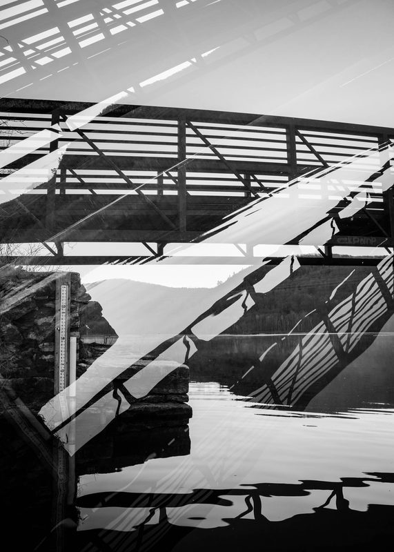 Black and white multiple exposure of a footbridge and its reflection over water